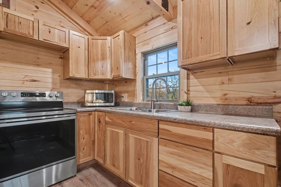 Kitchen featuring stainless steel appliances, wooden ceiling, light brown cabinetry, wood walls, and light wood-style flooring