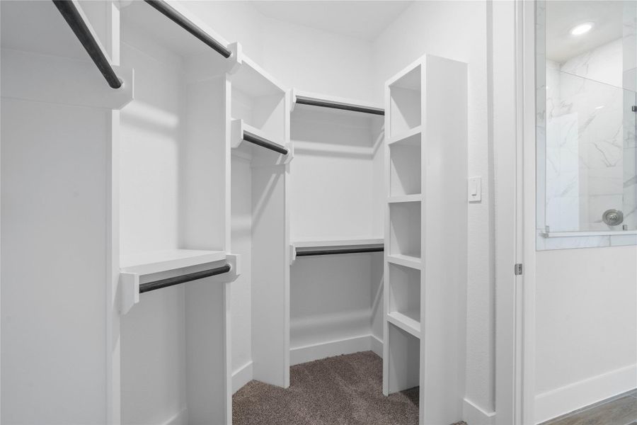 The spacious walk-in closet is equipped with clean white shelving and sturdy matte black hanging rods, offering extensive solutions for organizing an entire wardrobe. The spacious walk-in closet is equipped with clean white shelving and sturdy matte black hanging rods, offering extensive solutions for organizing an entire wardrobe.