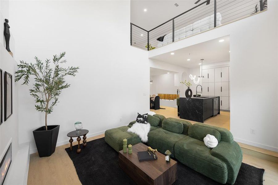 Living room with a high ceiling, light wood-type flooring, and recessed lighting