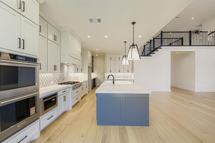 Kitchen with stainless steel appliances, white cabinetry, backsplash, recessed lighting, and light wood-style flooring Kitchen with stainless steel appliances, white cabinetry, backsplash, recessed lighting, and light wood-style flooring