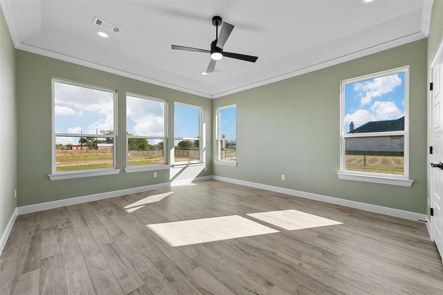 Second living or 4th bedroom with ceiling fan, light wood-type flooring, ornamental molding, and a wealth of natural light