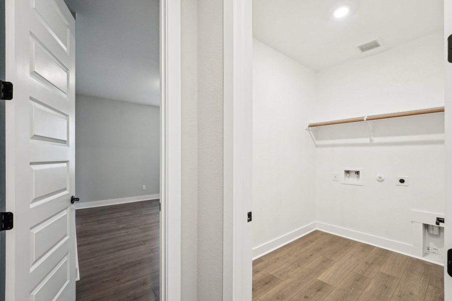 Washroom featuring electric dryer hookup, gas dryer hookup, washer hookup, wood finished floors, and recessed lighting Washroom featuring electric dryer hookup, gas dryer hookup, washer hookup, wood finished floors, and recessed lighting