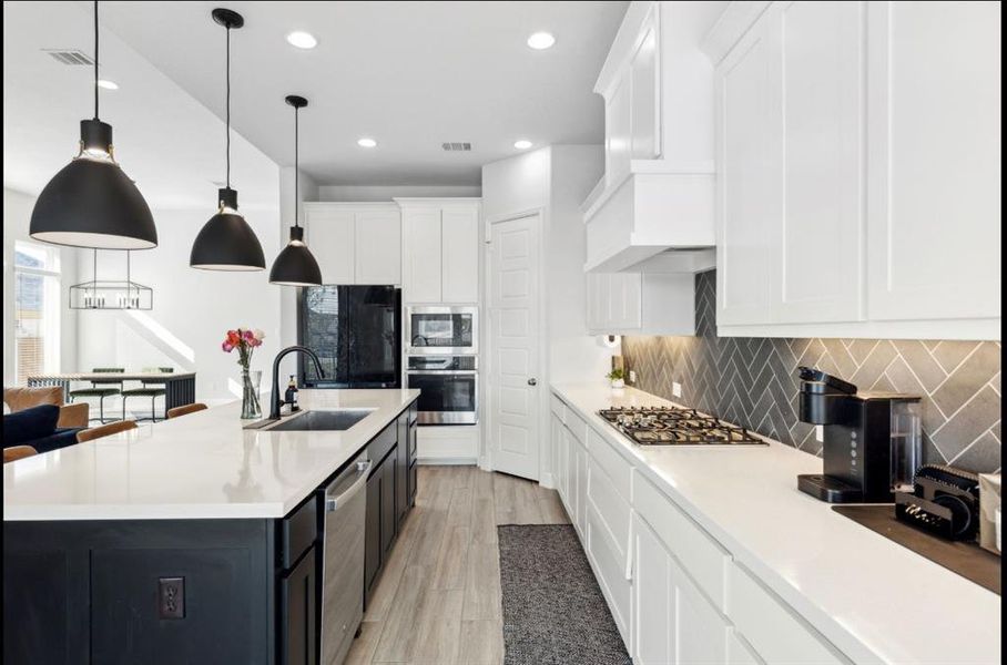 Kitchen with white cabinets, decorative light fixtures, decorative backsplash, recessed lighting, and stainless steel appliances