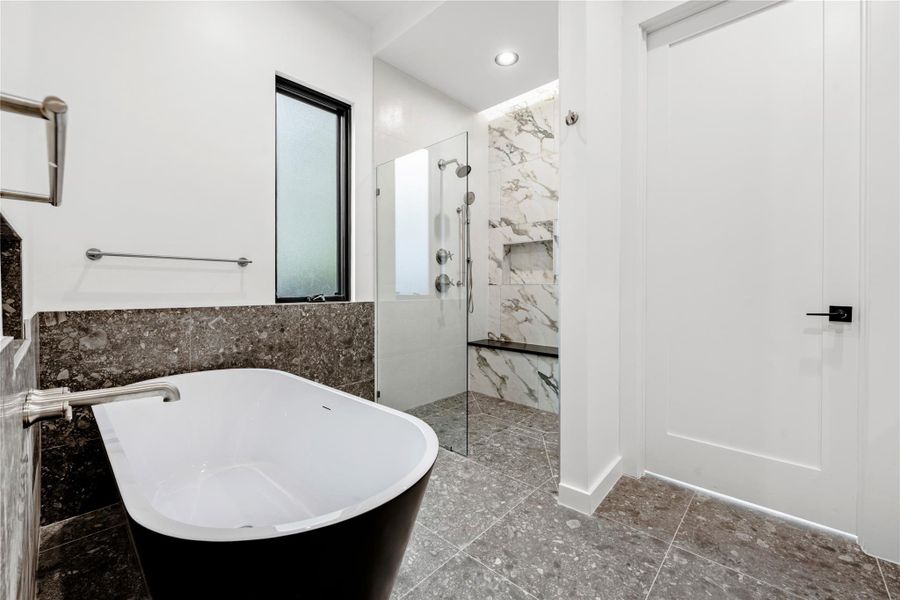 Full bathroom with a soaking tub, a marble finish shower, and tile walls