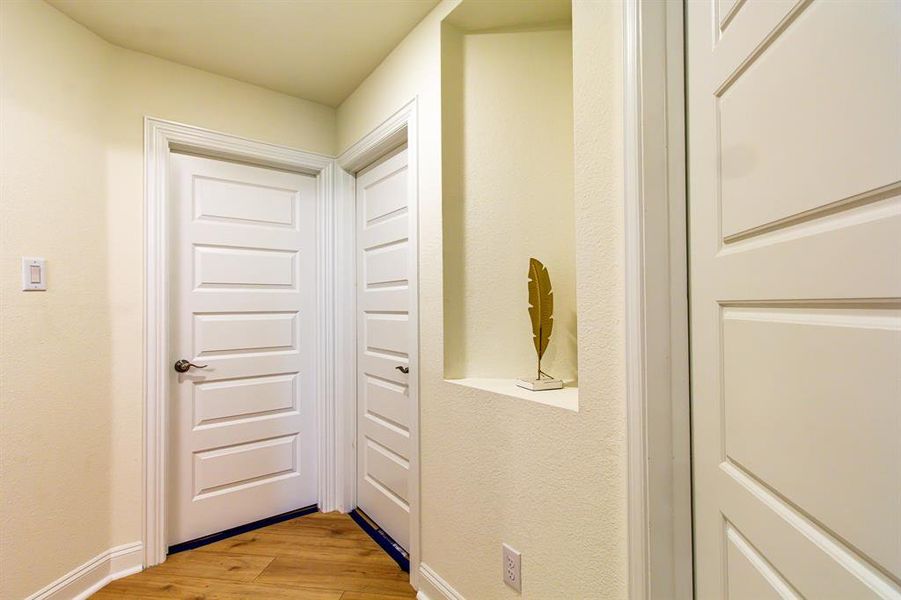 Corridor featuring light wood-style flooring and a textured wall Corridor featuring light wood-style flooring and a textured wall