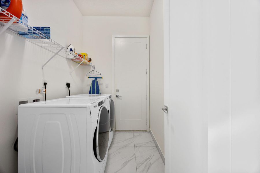 Washroom featuring light marble finish flooring and washer and clothes dryer