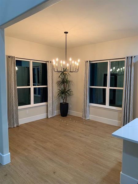 Unfurnished dining area featuring an inviting chandelier and hardwood / wood-style flooring