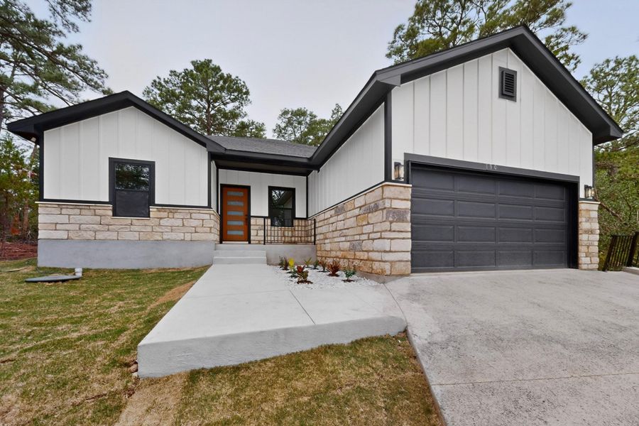 Modern home featuring board and batten siding, stone accents, and an attached garage with concrete driveway. Modern home featuring board and batten siding, stone accents, and an attached garage with concrete driveway.