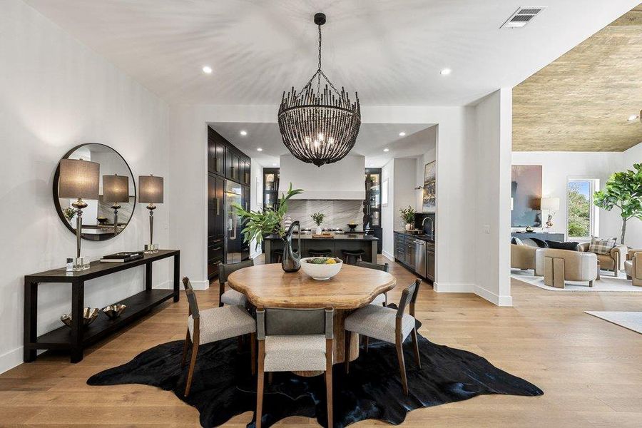 An open-concept living space features hardwood flooring and an eye-catching chandelier above the dining area.
