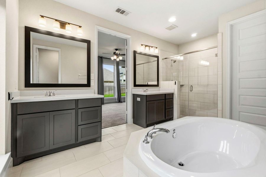 The spa-inspired primary bath features dual vanities with double sinks, a relaxing soaking tub, a separate glass-enclosed shower, and a spacious walk-in closet.