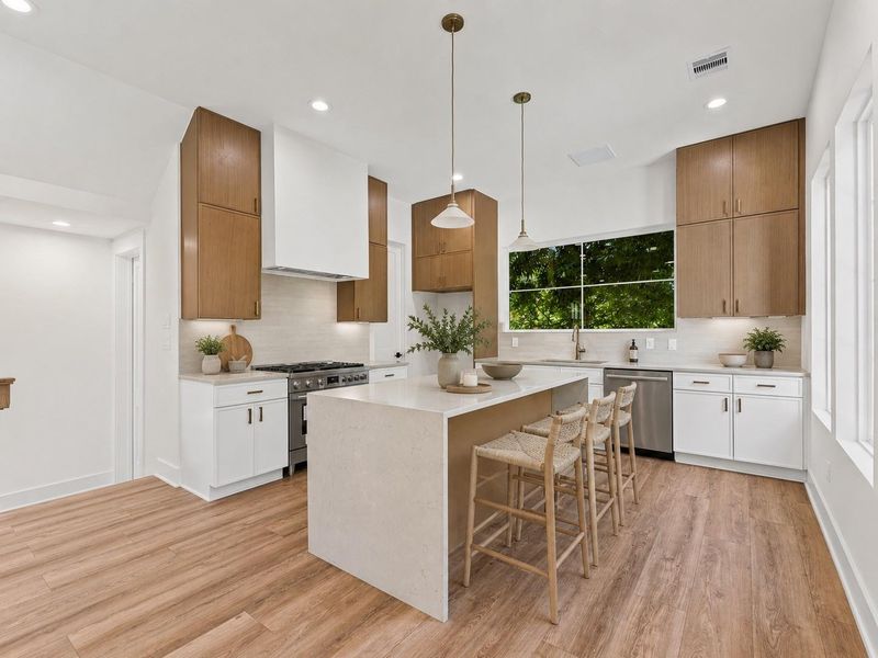 Kitchen features large waterfall island with quartz countertops and a walk-in pantry. Kitchen features large waterfall island with quartz countertops and a walk-in pantry.