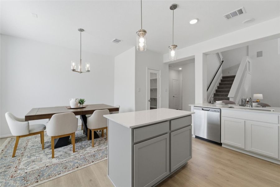 An open concept design seamlessly connects the dining area and kitchen, illuminated by stylish pendant lights. An open concept design seamlessly connects the dining area and kitchen, illuminated by stylish pendant lights.