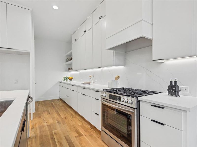 Kitchen with light hardwood / wood-style floors, white cabinetry, tasteful backsplash, and stainless steel appliances