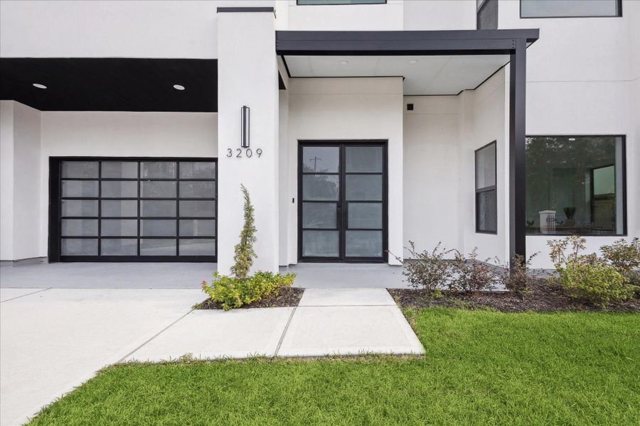 A close-up of the home captures the refined craftsmanship of the front door and the inviting appeal of the home’s exterior.
