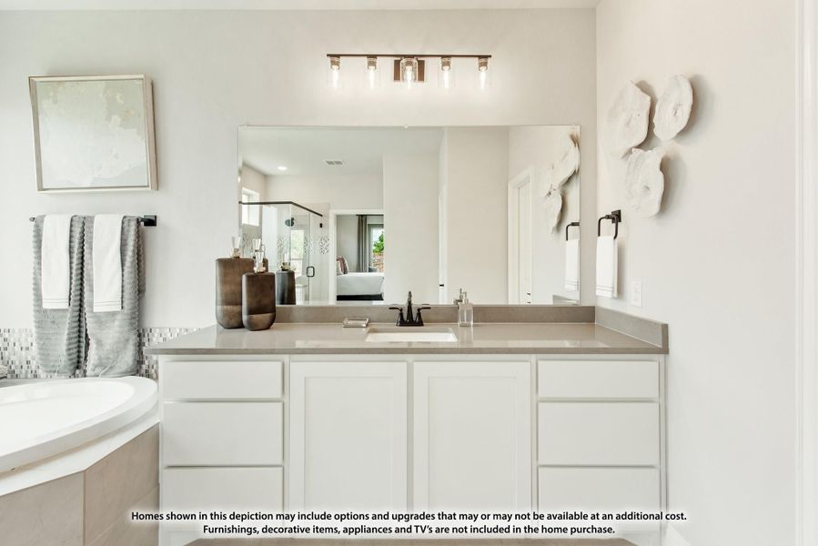 Bathroom vanity with white cabinets, gray countertop, large mirror, and soaking tub beside mosaic tile accent wall.