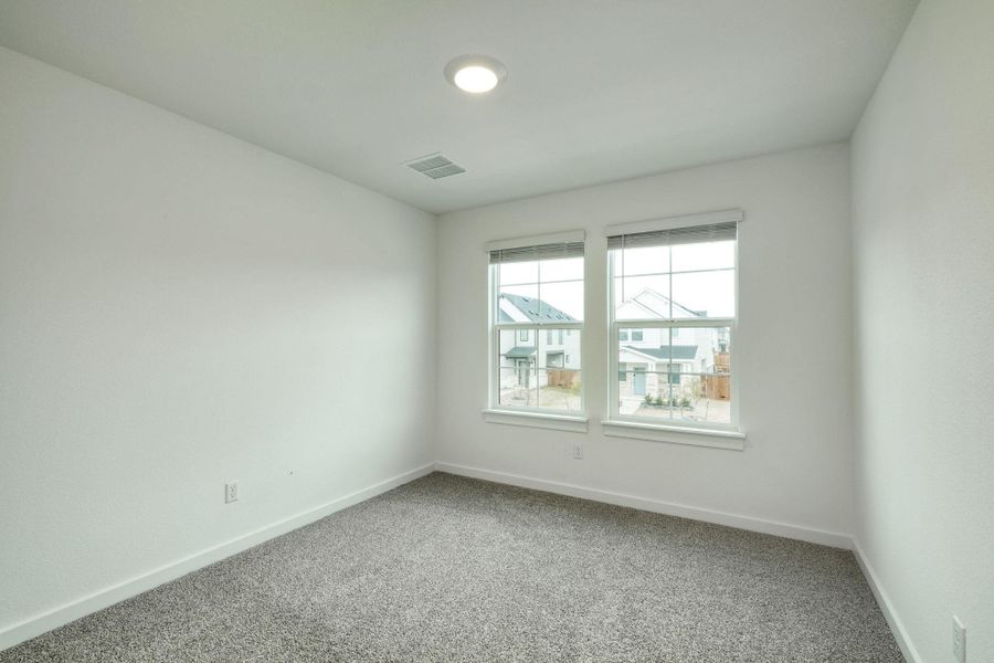 Carpeted spare room featuring visible vents and baseboards