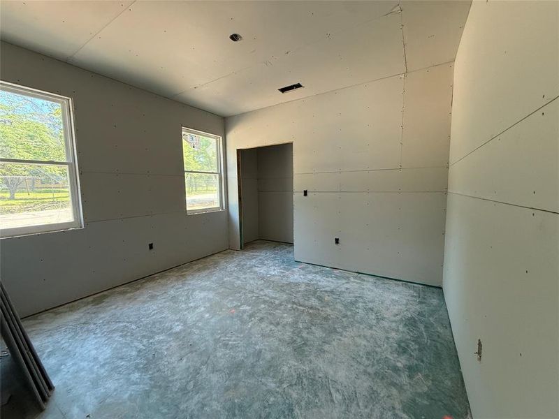 Interior room featuring two large windows, drywall-finished walls, and concrete flooring