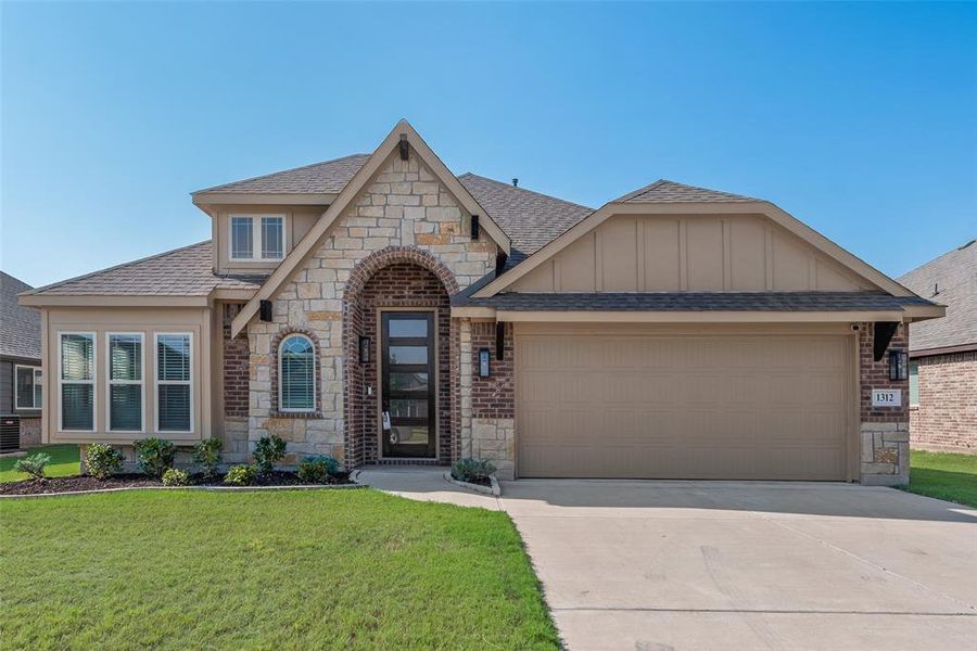 View of front of property featuring stone siding, roof with shingles, an attached garage, a front yard, and concrete driveway View of front of property featuring stone siding, roof with shingles, an attached garage, a front yard, and concrete driveway