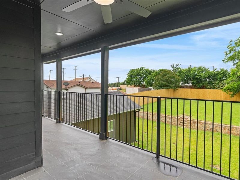 Expansive covered balcony featuring dark gray siding, a ceiling fan with integrated lighting, recessed ceiling lights, and dark gray tile flooring