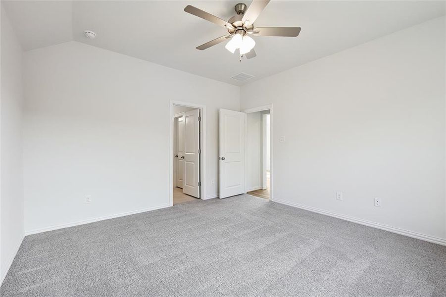 Unfurnished bedroom featuring light carpet, ceiling fan, and lofted ceiling