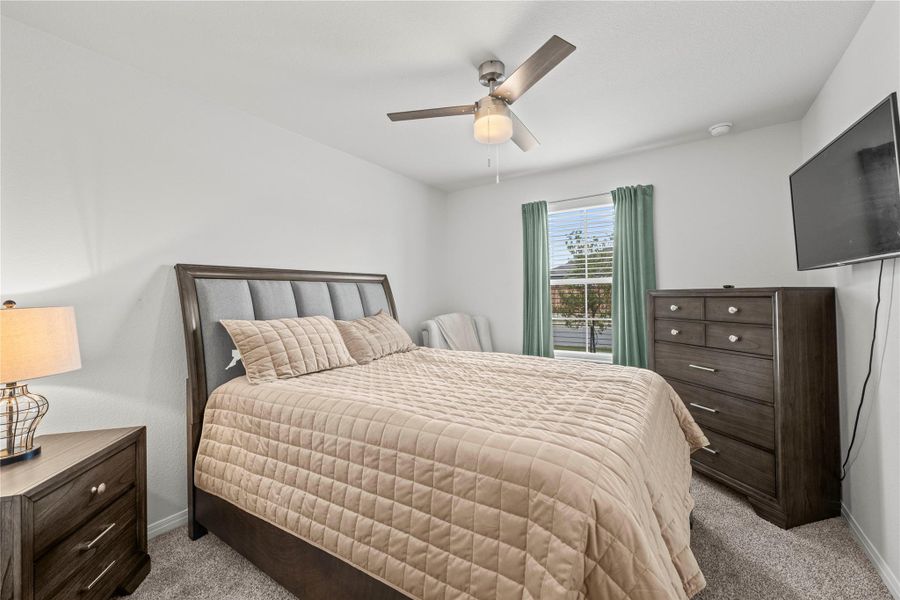 A tranquil bedroom provides comfort with soft carpeting and a ceiling fan for year-round ease.