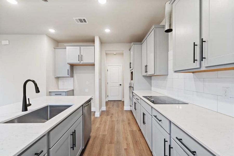 Kitchen featuring tasteful backsplash, sink, stainless steel appliances, light stone countertops, and light wood-type flooring