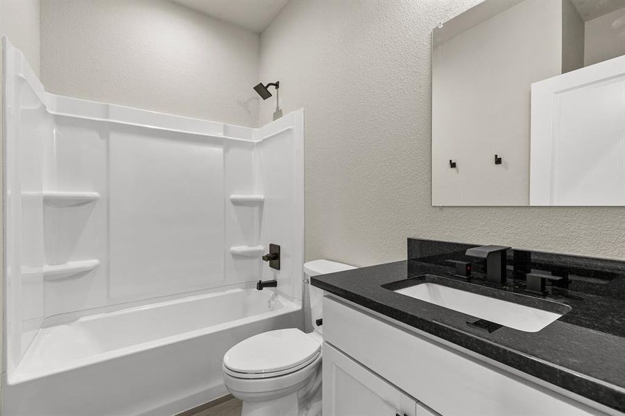 Full bath featuring a textured wall, vanity, and shower / washtub combination Full bath featuring a textured wall, vanity, and shower / washtub combination