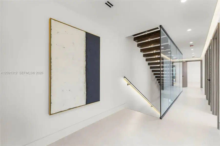Staircase featuring open-riser wood treads, a full-height glass panel partition, a sleek wall-mounted handrail with integrated LED lighting, and large-format tile flooring Staircase featuring open-riser wood treads, a full-height glass panel partition, a sleek wall-mounted handrail with integrated LED lighting, and large-format tile flooring