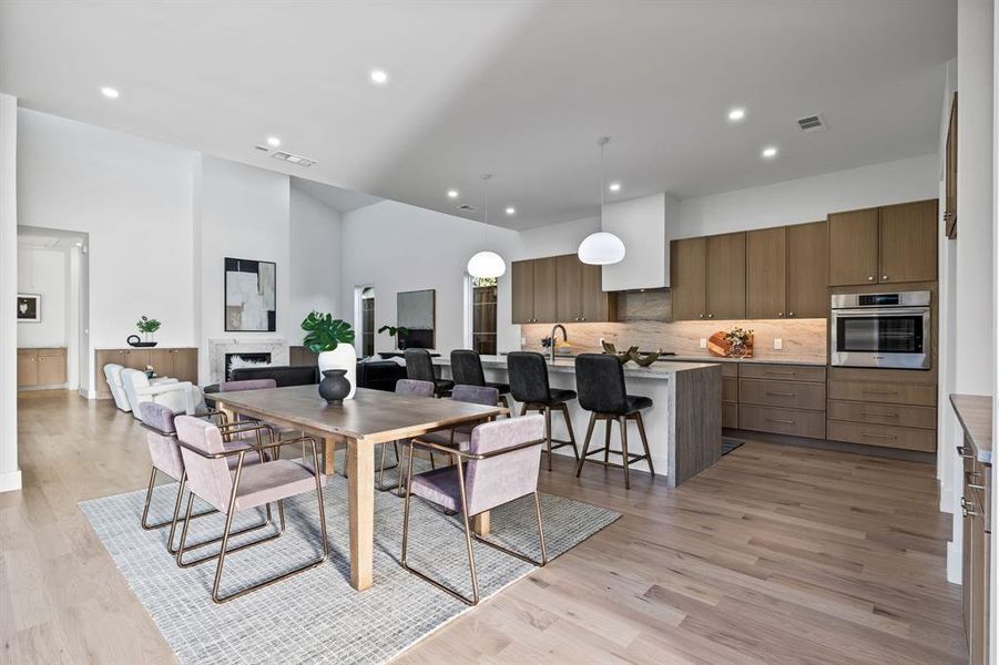 Dining area with a towering ceiling, sink, and light hardwood / wood-style flooring