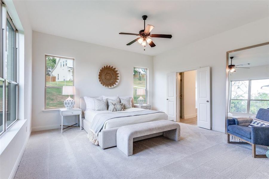 Bedroom with light colored carpet, ceiling fan, and multiple windows