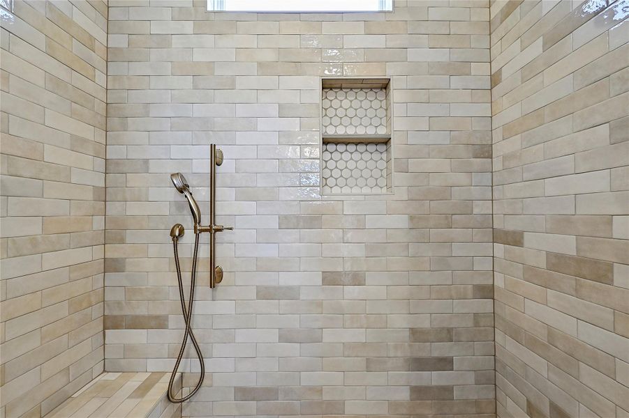 Roomy shower with contollers at the entry door, shower head, shower wand and sitting bench.  The tile is really cool looking too.