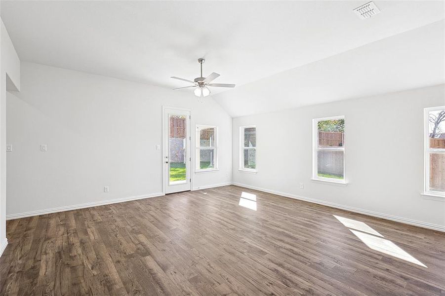 Spare room with dark hardwood / wood-style flooring, plenty of natural light, lofted ceiling, and ceiling fan