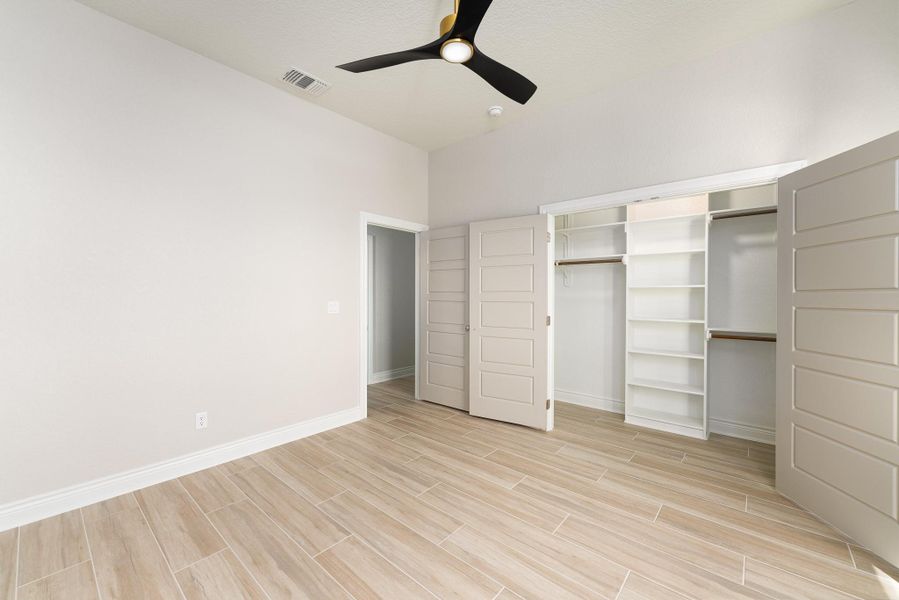 Unfurnished bedroom with wood finish floors, a ceiling fan, and a closet Unfurnished bedroom with wood finish floors, a ceiling fan, and a closet