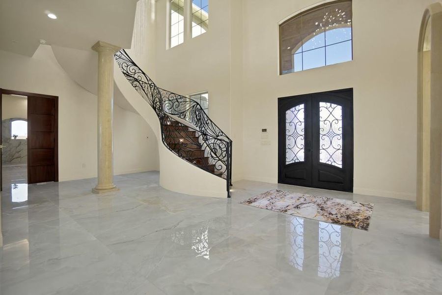 Foyer entrance with ornate columns, a towering ceiling, and french doors