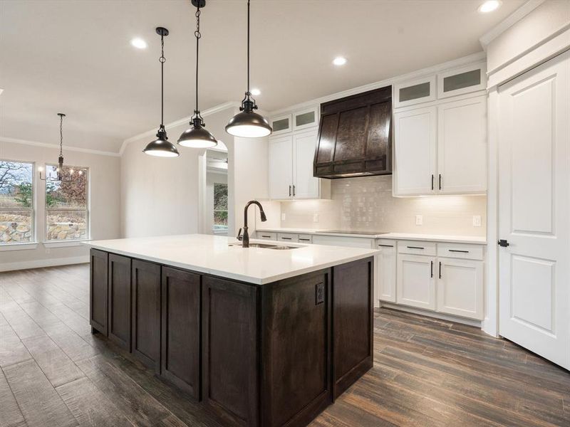 Kitchen with dark wood-type flooring, sink, a kitchen island with sink, cooktop, and custom exhaust hood