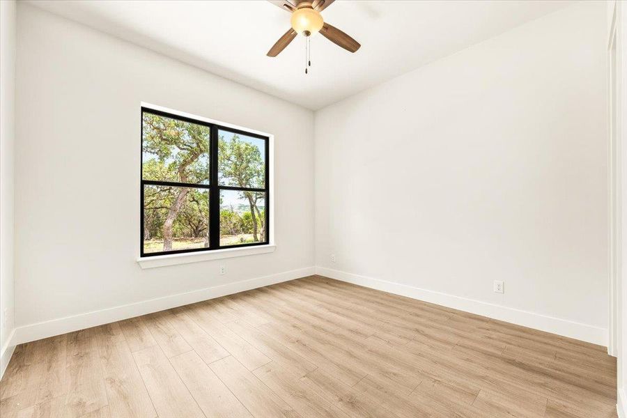 A well-lit room showcasing rich wood flooring and a refreshing tree-filled view.