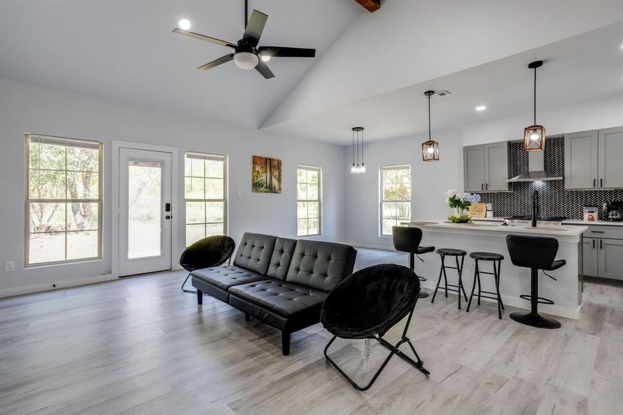 Living area featuring light wood finished floors, high vaulted ceiling, recessed lighting, ceiling fan, and beamed ceiling Living area featuring light wood finished floors, high vaulted ceiling, recessed lighting, ceiling fan, and beamed ceiling