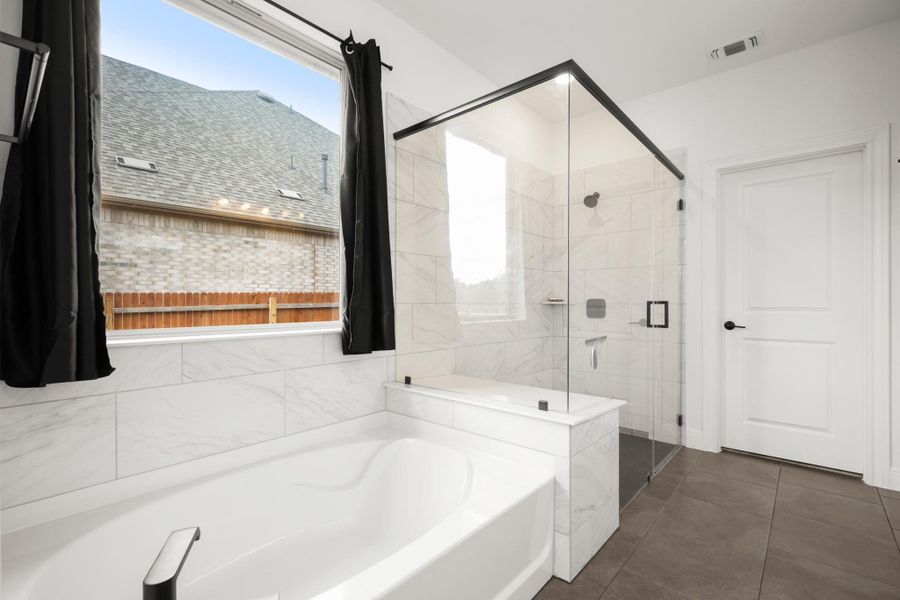 Full bath featuring a bath, a shower stall, and dark tile patterned flooring Full bath featuring a bath, a shower stall, and dark tile patterned flooring