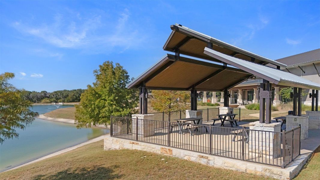 Stone patio with metal fencing, featuring two picnic tables under a contemporary covered structure Stone patio with metal fencing, featuring two picnic tables under a contemporary covered structure