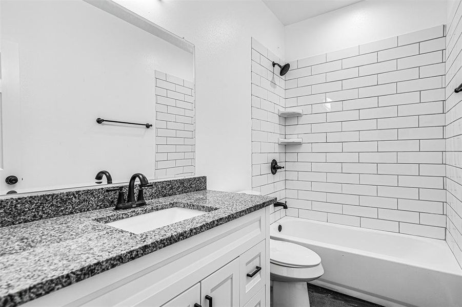 Full bathroom with toilet, vanity, and tiled shower / bath