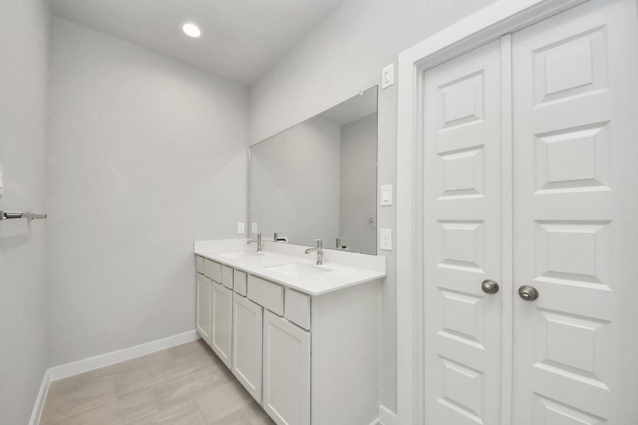 Escape to a spa-like oasis in this primary bathroom. Enjoy a walk-in shower with tile surround, a separate garden tub with custom detailing, and an elegant vanity featuring light countertops, modern hardware, and beautiful vanity lights. Experience luxury and relaxation in every detail. Sample photo of completed home with similar floor plan. Actual colors and selections may vary.