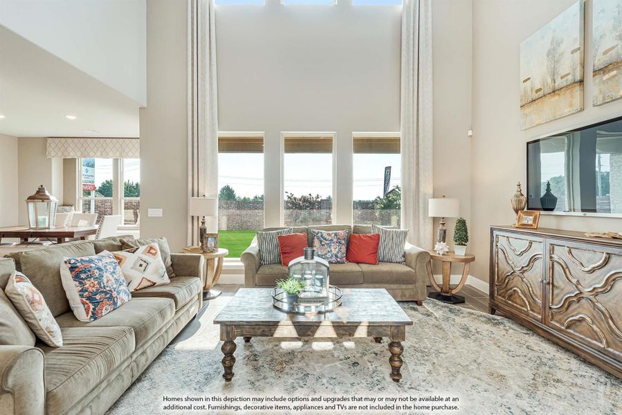 Living room with two-story ceiling, large windows, two sofas, wood coffee table, and wall-mounted TV