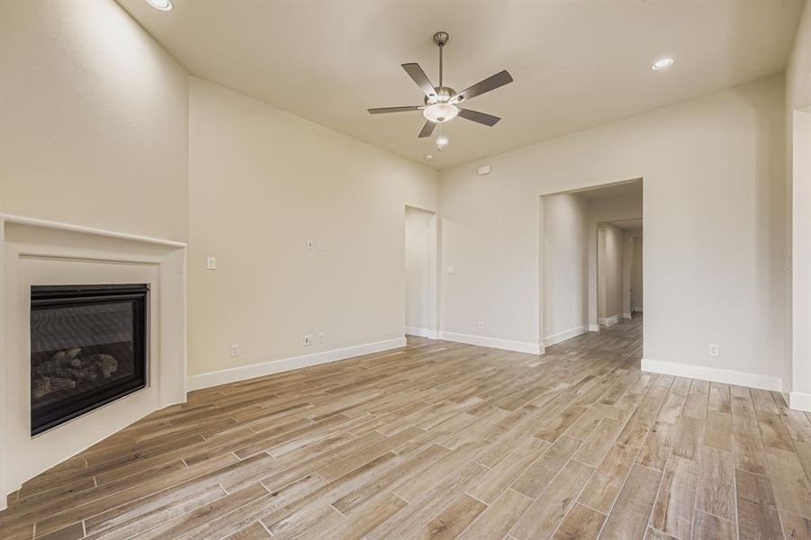 Unfurnished living room with recessed lighting, light wood-style floors, a ceiling fan, and a glass covered fireplace