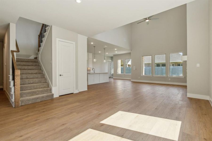 Unfurnished living room with light wood-type flooring, ceiling fan, a high ceiling, and sink