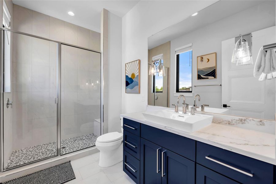 Bathroom five: Contemporary bathroom featuring a spacious glass-enclosed shower with pebble flooring and light tile walls