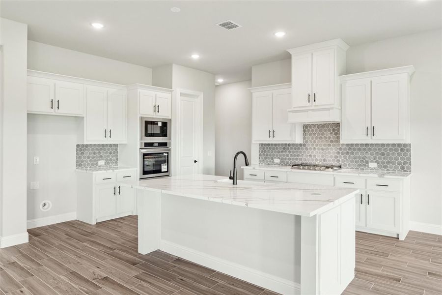 White kitchen with center island, marble countertops, stainless steel appliances, and gray hexagon tile backsplash White kitchen with center island, marble countertops, stainless steel appliances, and gray hexagon tile backsplash