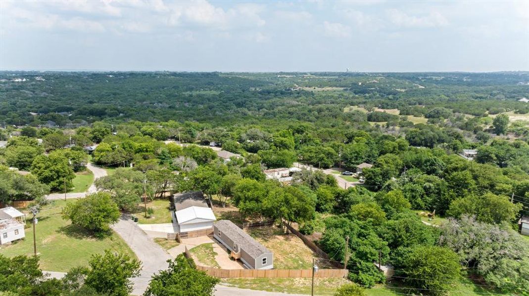 Expansive aerial perspective showcasing a residential area with lush green tree cover and a distant wooded landscape