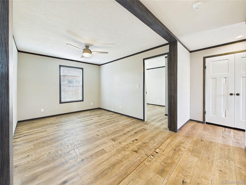 Open family area with wide-plank flooring, ceiling fan, and a flexible layout that connects seamlessly to adjacent spaces.