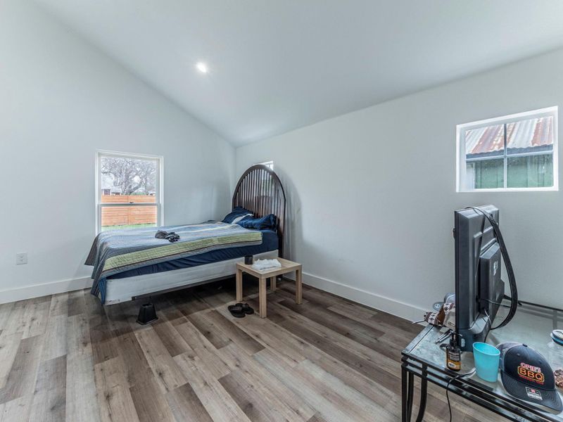 Bedroom with light wood finished floors, vaulted ceiling, and recessed lighting