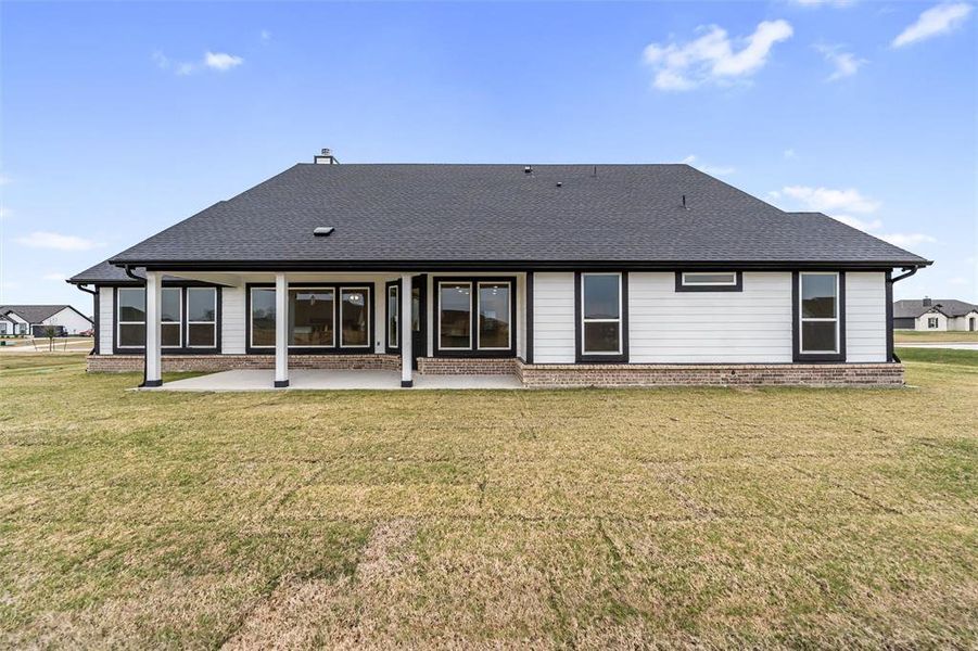 Back of property with a patio area, roof with shingles, and a yard